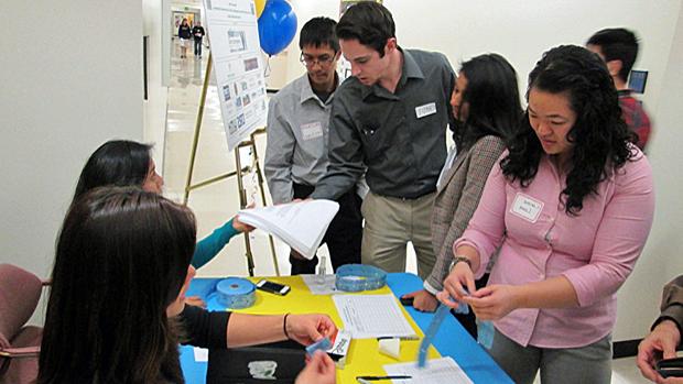 Students and faculty working together on a project around a table.