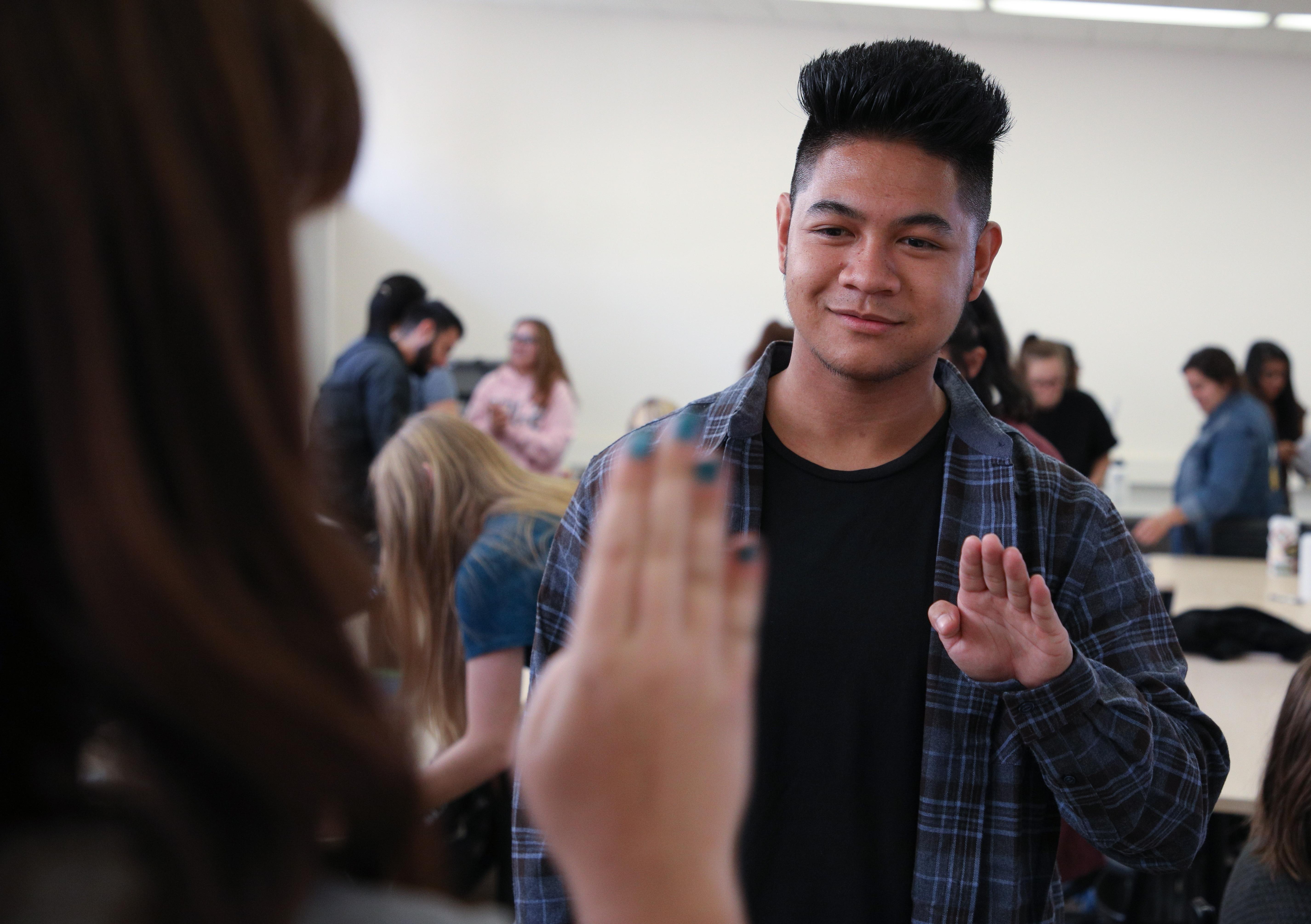 Two students practice using hand signals in a classroom setting.